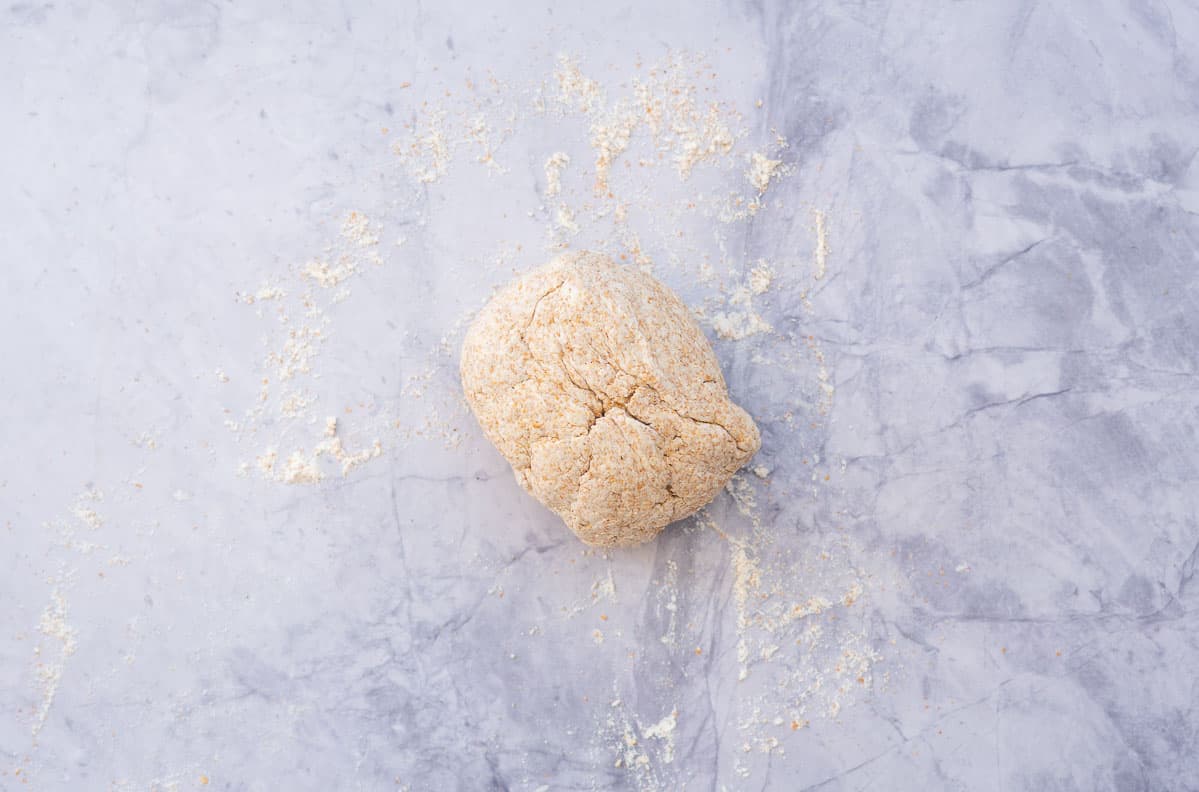 A ball of wholemeal yogurt dough on a floured marble bench.