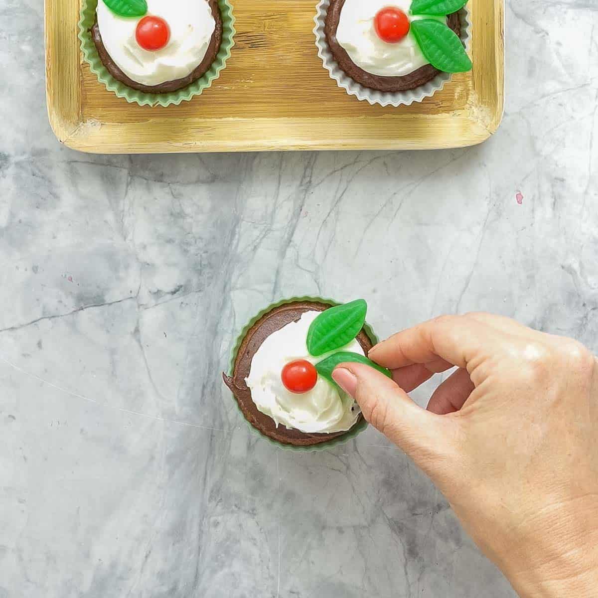 Decorate the frosted cupcake with 1 Jaffa (or red ball-shaped sweet) and 1-2 spearmint leaves to look like a sprig of holly