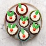 A round plate with seven cupcakes decorated to look like figgy puddings.