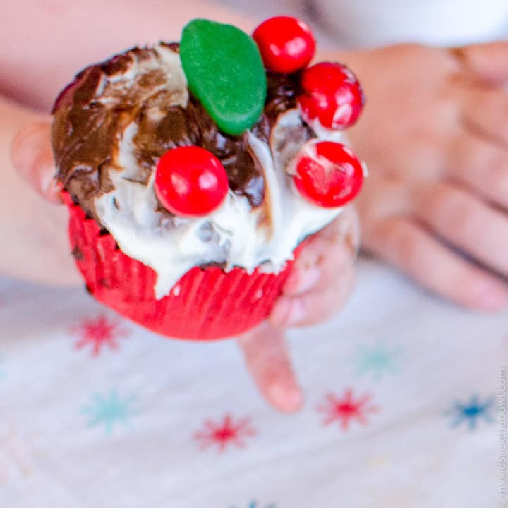 A cupcake messily decorated with candy and frosting by a child to look a little like a figgy pudding.
