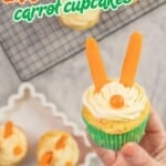 Woman's hand holding a cupcake with icing piped on top, carrot sticks as ears and an orange lolly as a nose, text overlay: Easy Easter Bunny Carrot Cupcakes.