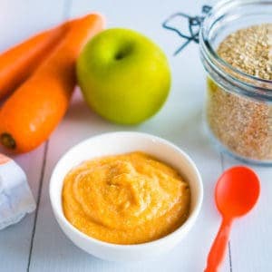 Small bowl of pureed carrot apple on benchtop, two carrots and a green apple next to the bowl.