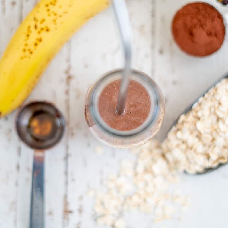 Healthy homemade chocolate milk ingredients, oats, cocoa, banana, maple syrup and milk