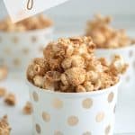 Caramel coloured popcorn in a white and gold polka dot cup with text overlay "Cinnamon Popcorn Vegan"