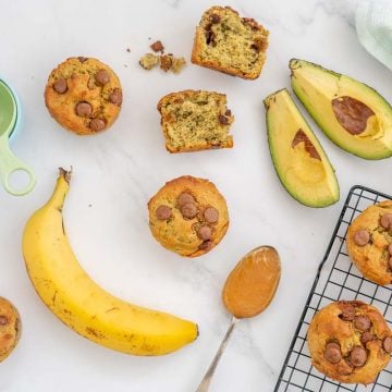 avocado muffin surrounded by ingredients and baking equipment on a bench top