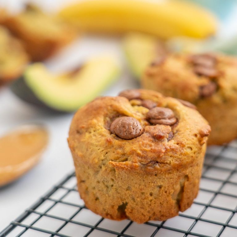 muffin sitting on a cooling rack with banana and avocados visible in the background
