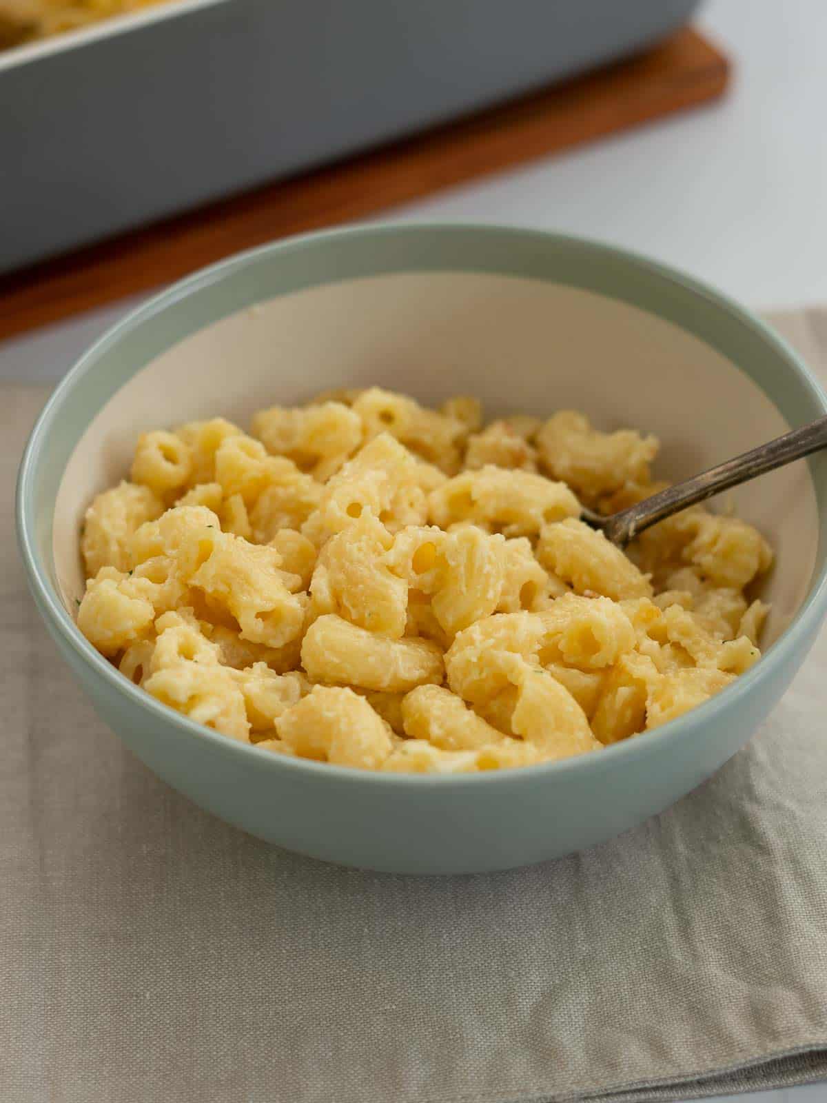 a bowl of mac and cheese sitting on a placemat with a spoon