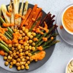 Plate with roasted veggies cut in long thin strips, carrot, asparagus, parsnip and chickpeas on top.