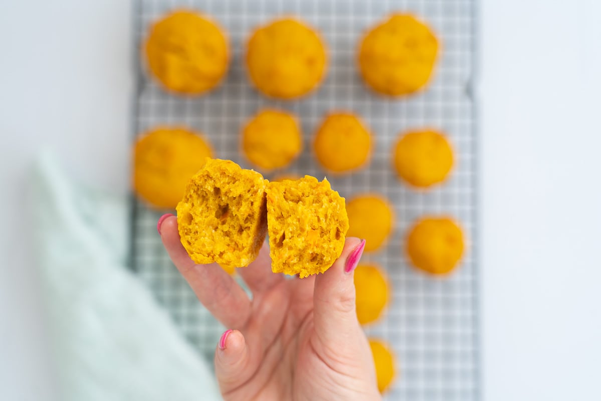womans hand holding a muffin which has been broken in half showing it's texture
