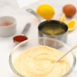 bowl of sriracha aioli with ingredients in the background, text overlay for pinterest