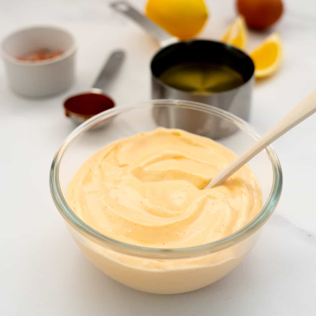 bowl of sriracha aioli on a marble bench top with ingredients in the background