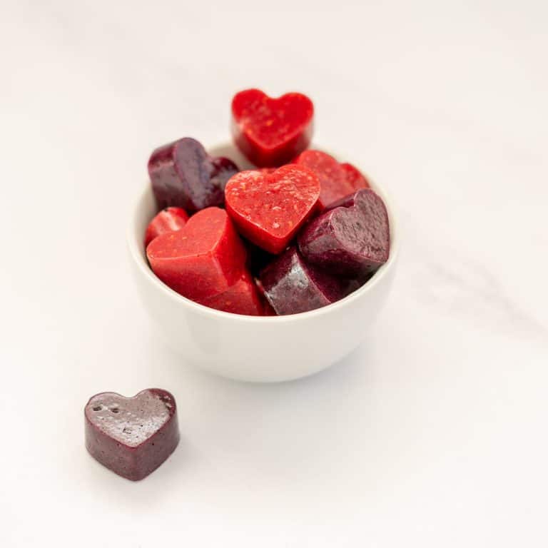 red and purple heart shaped fruit gummies in a white bowl