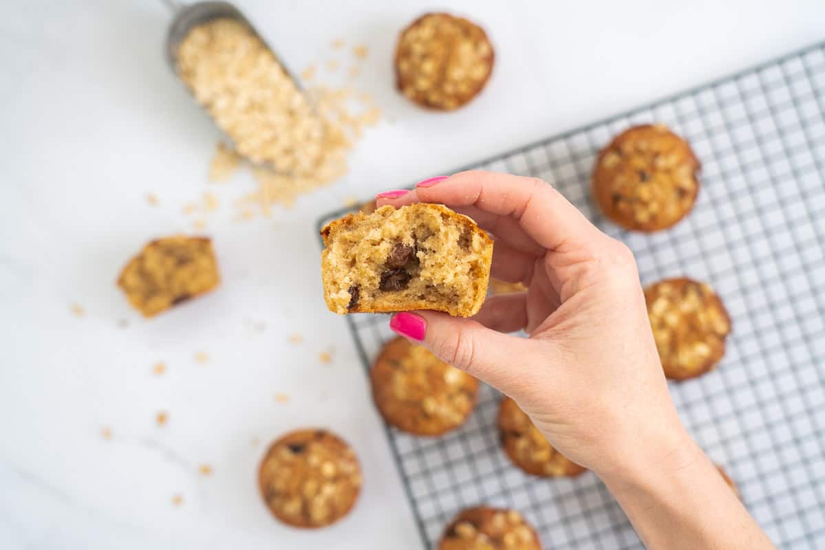 hand holding half an oatmeal muffin so that the cooked centre is displayed