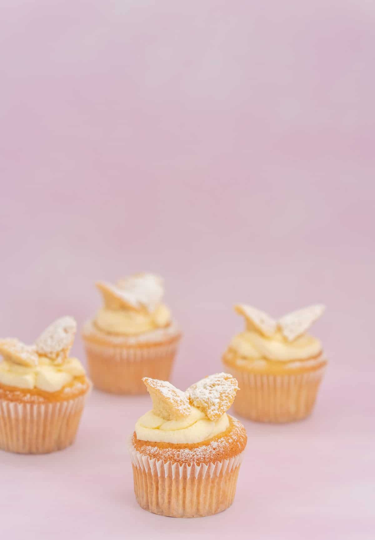 4 butterfly cupcakes on a pink background
