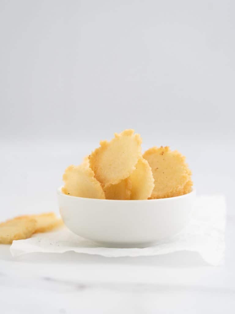 hoemade rice crackers in a white bowl on a marble bench top