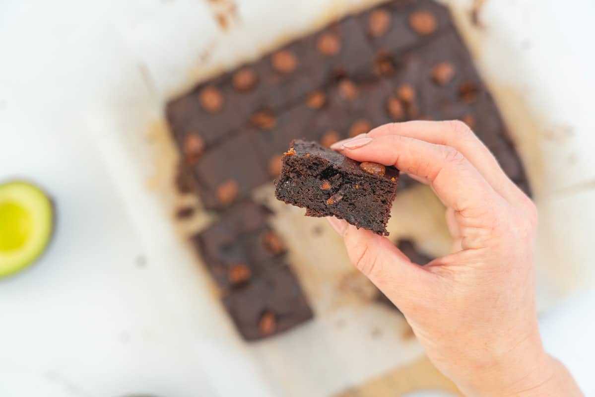 women's hand holding a piece of avocado brownie