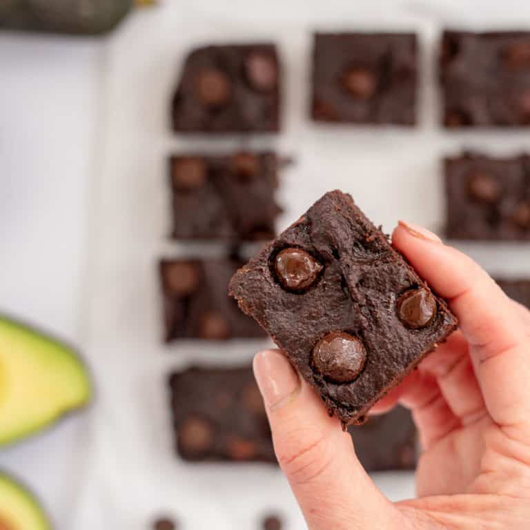women's hand holding a piece of avocado brownie