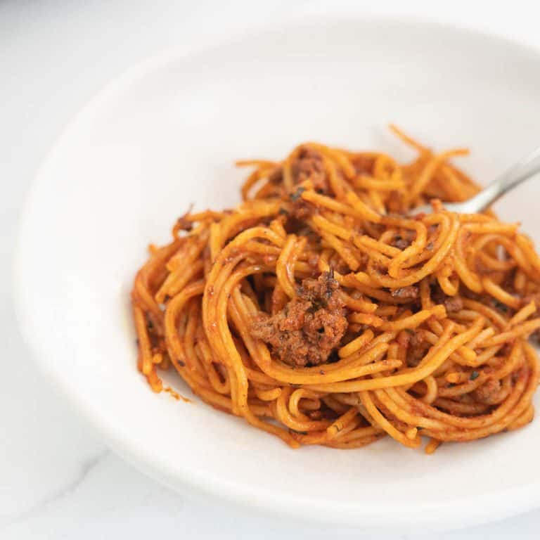 spaghetti bolognese in a white bowl with fork
