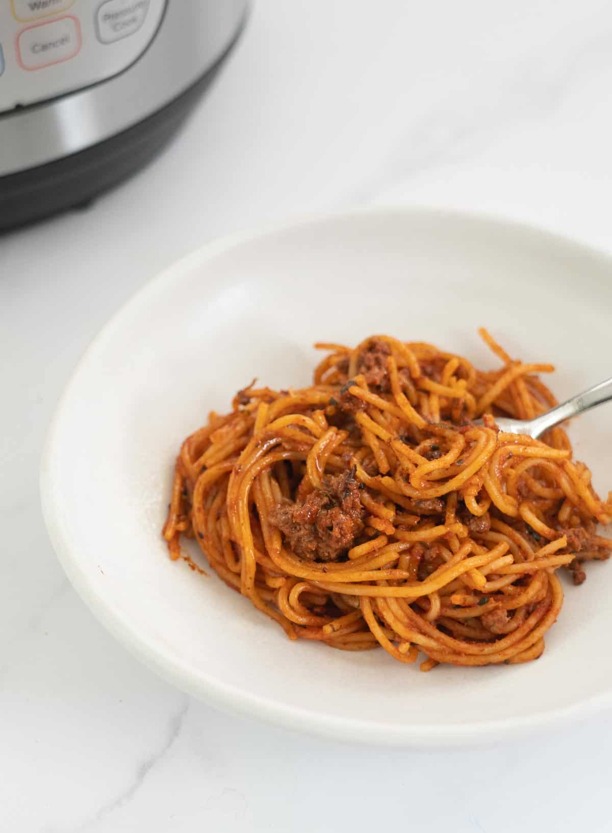 Bowl of spaghetti bolognese with an instant pot in the background