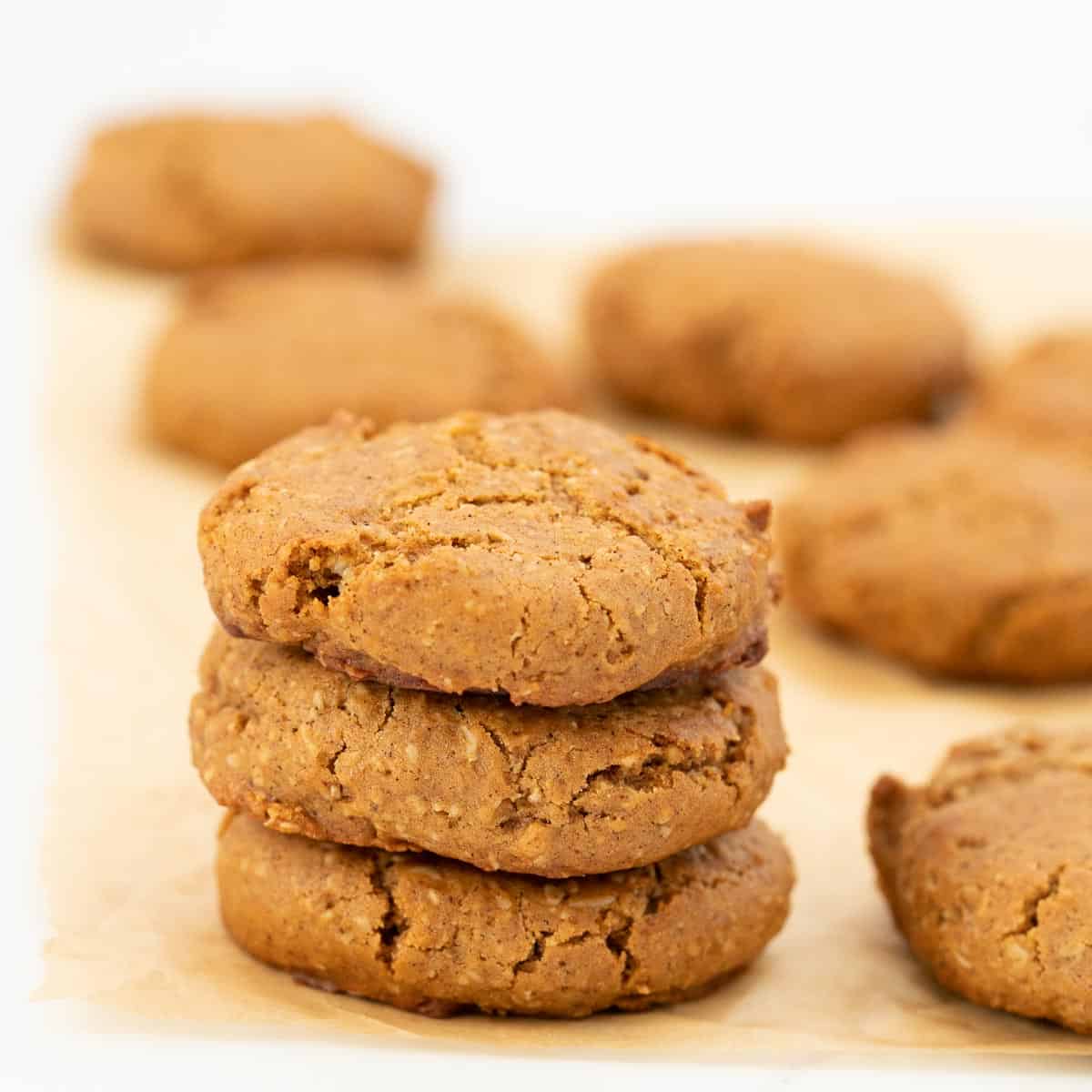 A stack of three cinnamon cookies sitting on parchment paper