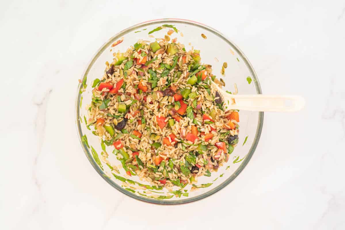 Large glass bowl filled with brown rice salad, red and green ingredients visible.