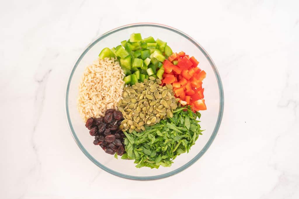 Large glass bowl of brown rice, capsicum, pumpkin seeds, cranberries and spinach