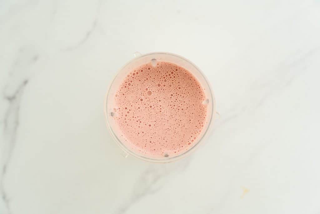top down shot of a pink blended strawberry milk shake in a Nutribullet blender cup.