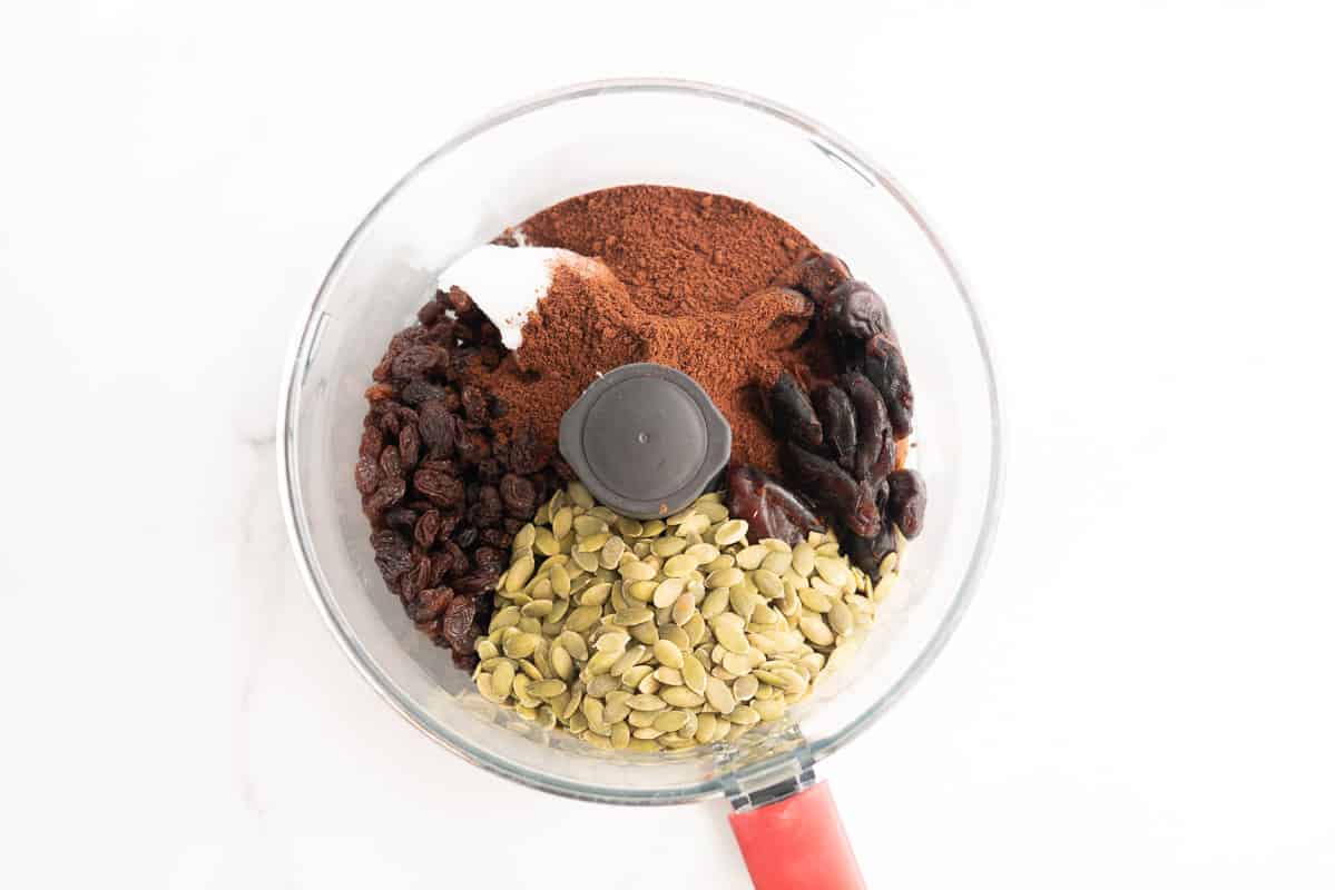 Pumpkin seeds, dates, raisins, milo, and coconut oil in a food processor.