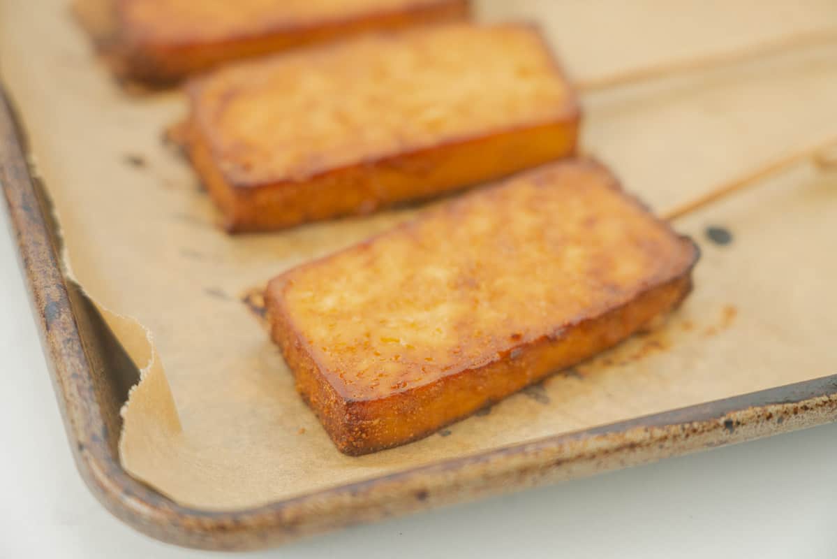 Golden brown baked tofu on a baking paper lined tray.
