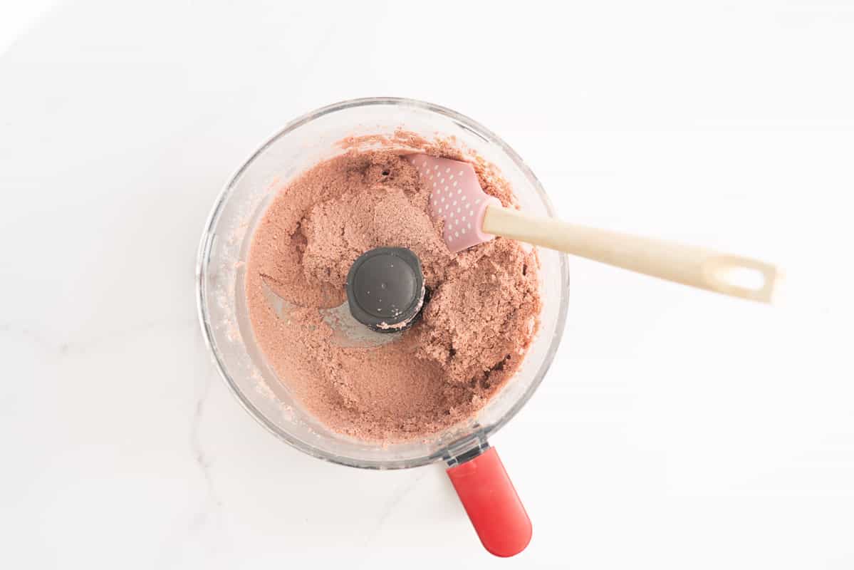 A pink dough in a food processor.