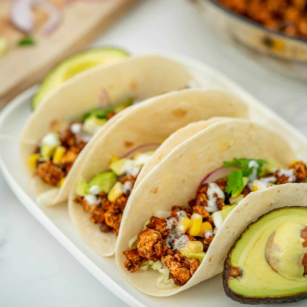 3 soft tacos filled with Mexican tofu crumbles on a white platter.
