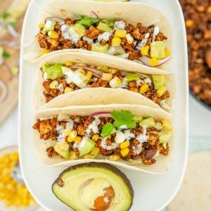 3 soft tacos filled with Mexican tofu crumbles on a white platter.