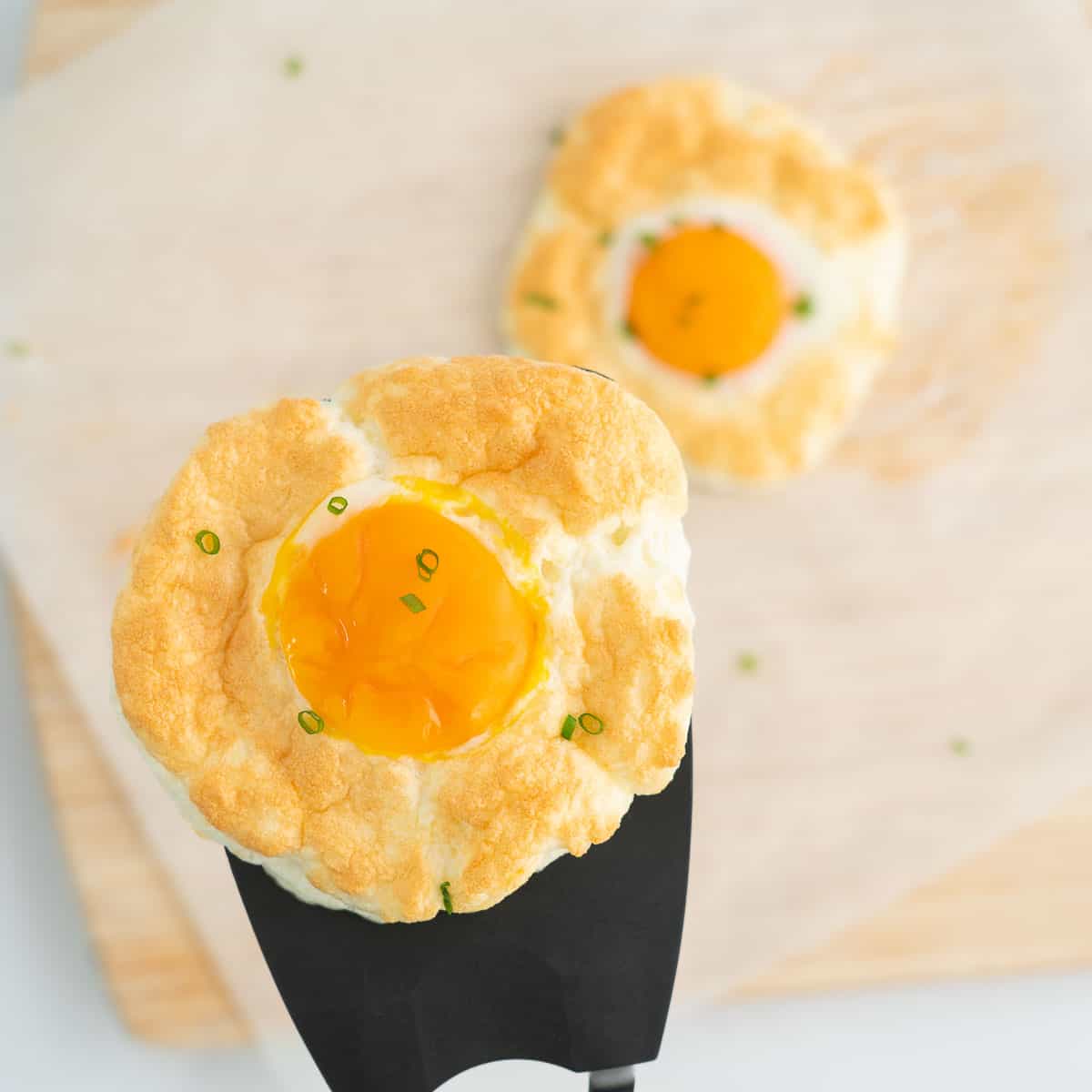 A cloud egg lifted up on a large black spatula.