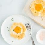 A cloud egg sprinkled with finely chopped chives on a white plate.