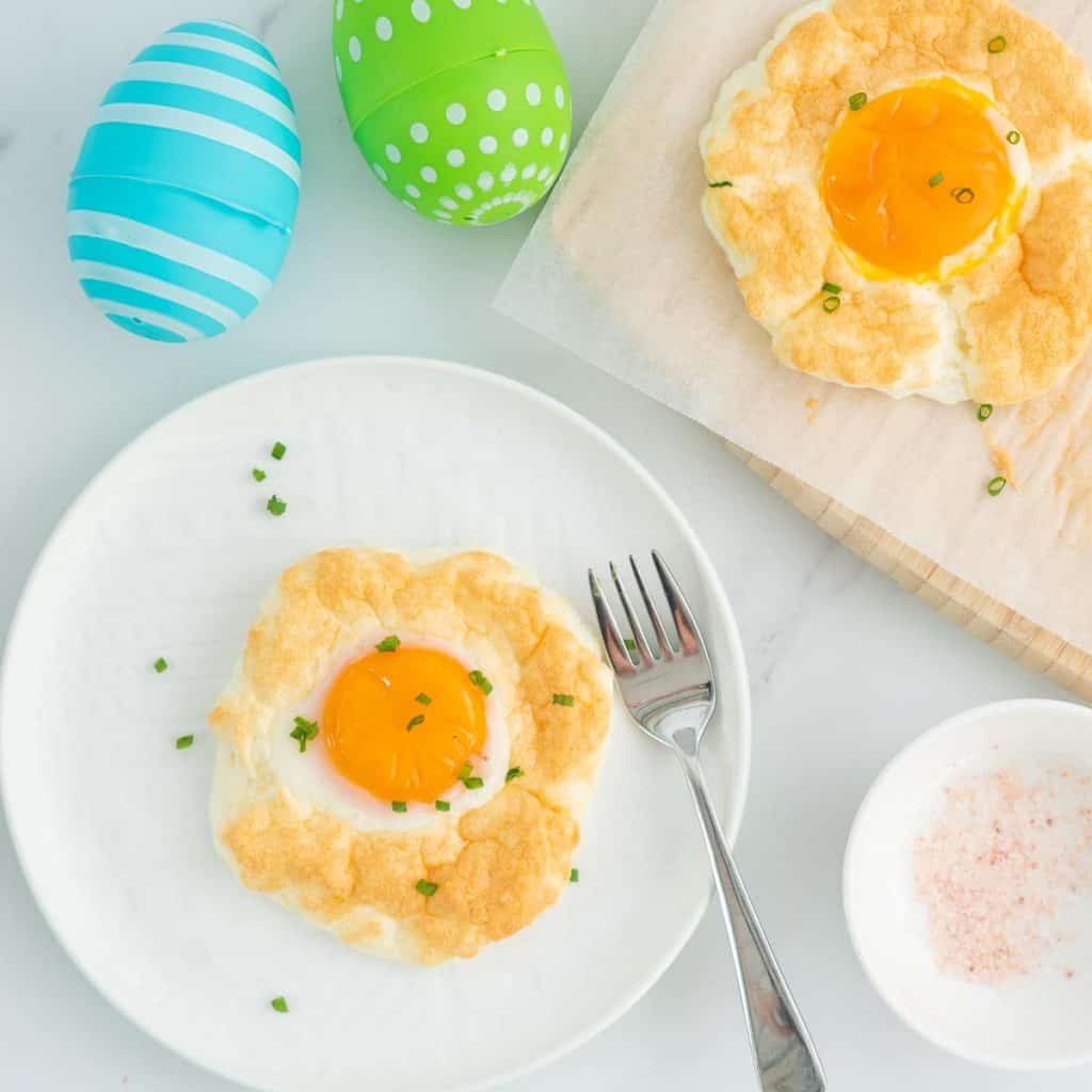 A cloud egg on a white plate with colourful plastic easter eggs.