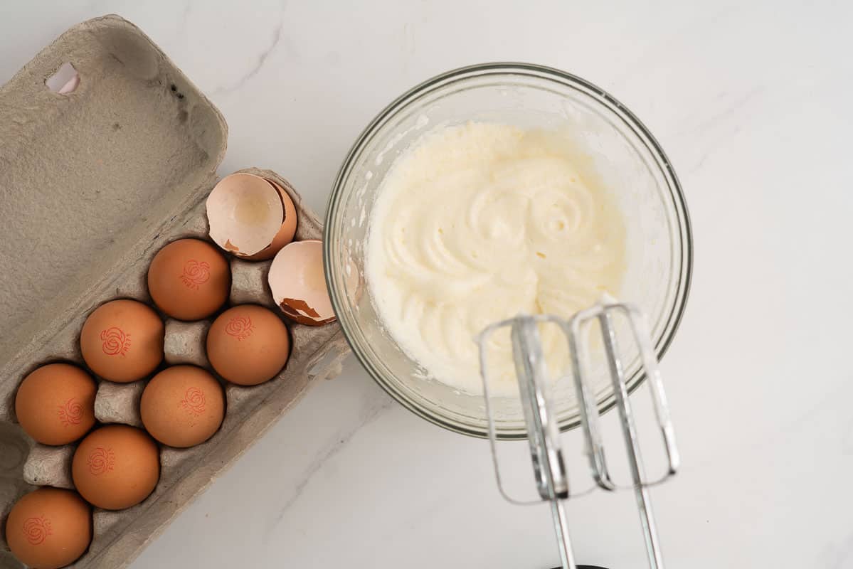 Egg and Parmesan cheese beaten together in a glass bowl.