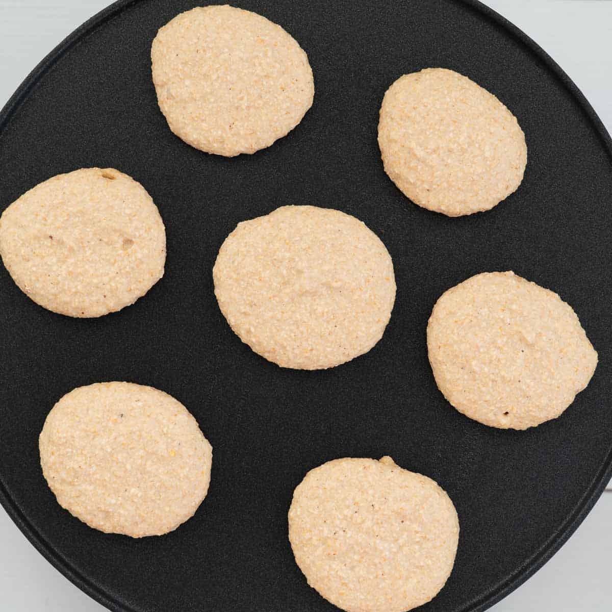 Pancakes cooking on a pancake pan.