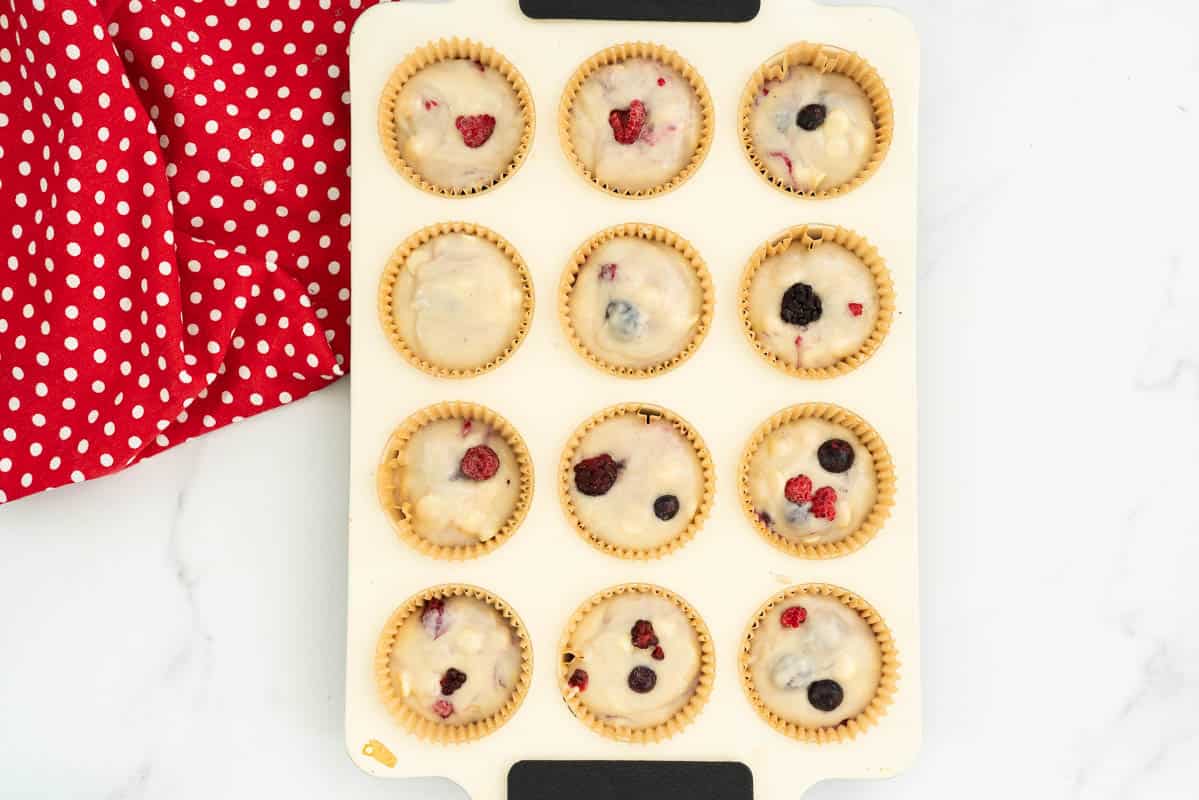 berry muffin batter portioned into a 12 cup muffin tray.