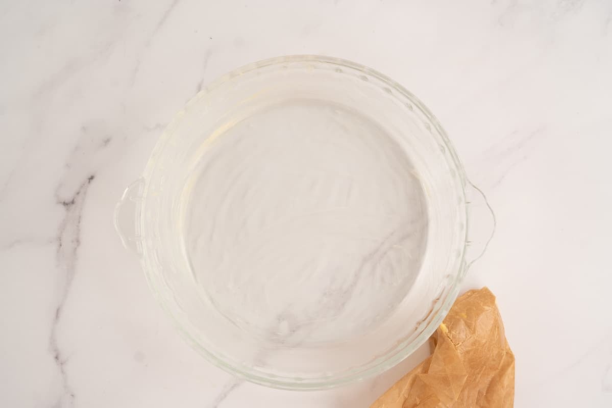 A round glass pie dish greased with butter.
