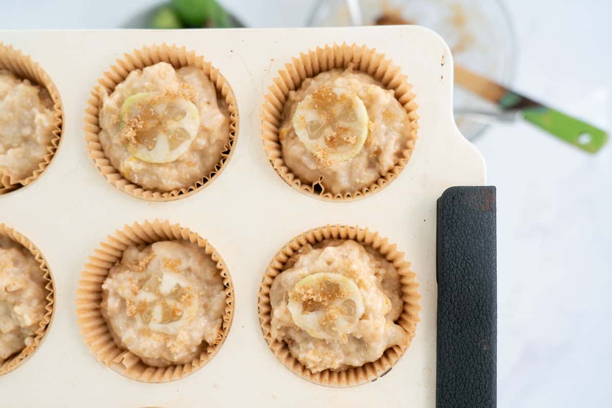 Close up showing a slice of feijoa on the top of an uncooked muffin with a sprinkling of brown sugar.