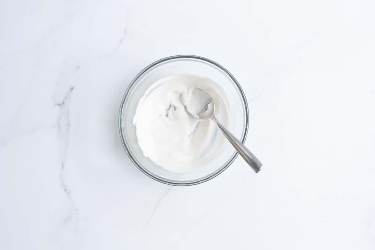 Coconut cream in a glass bowl with a dessert spoon.
