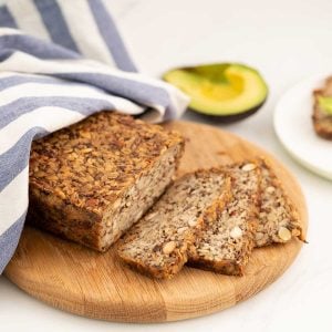 Seeded oat bread sliced on a wooden chopping board.
