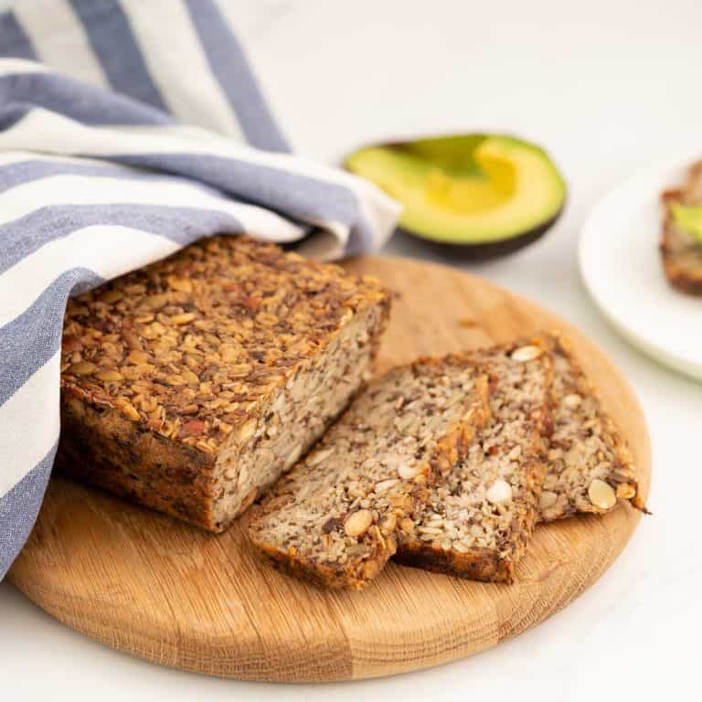 Seeded oat bread sliced on a wooden chopping board.