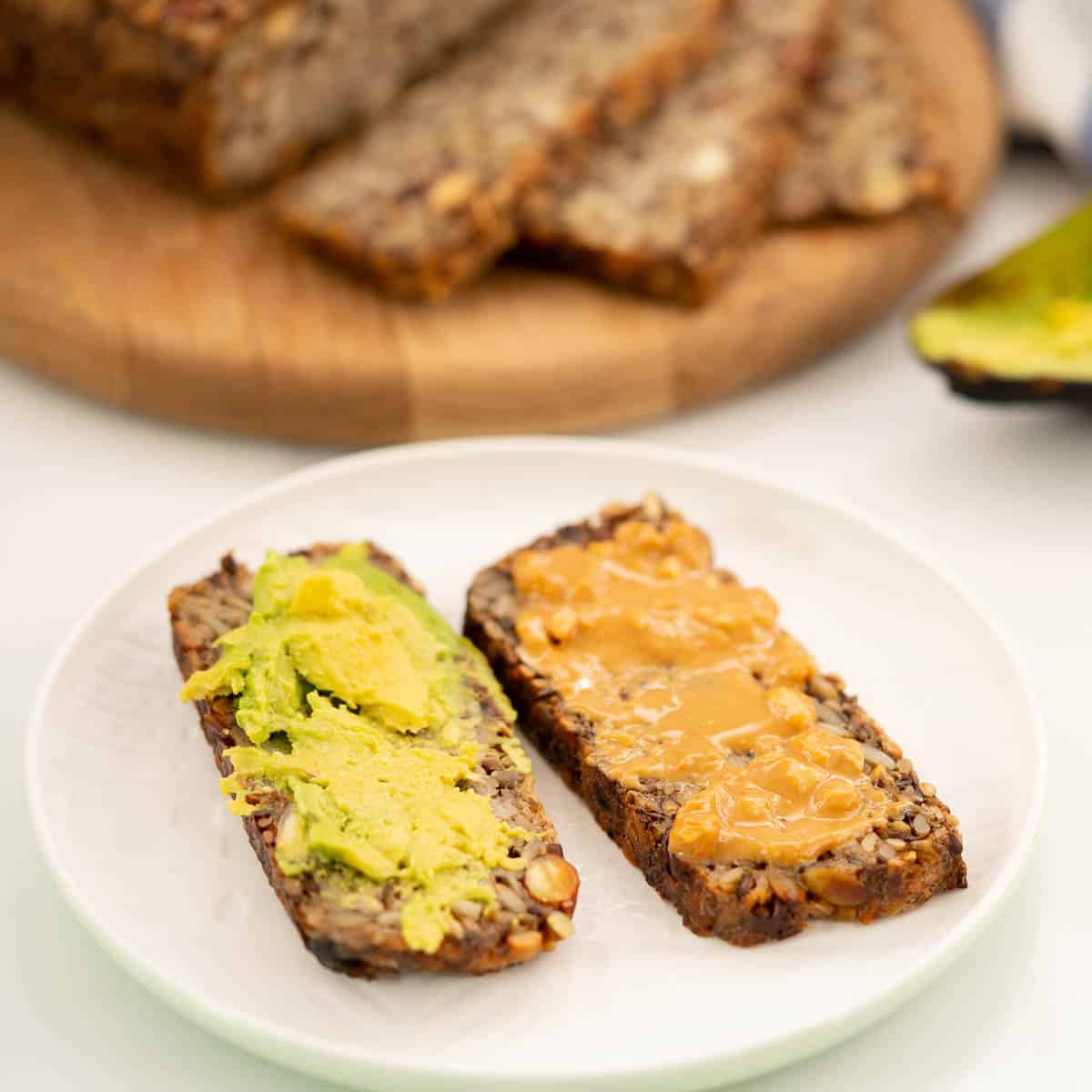 2 slices of oat toast spread with avocado and peanut butter.
