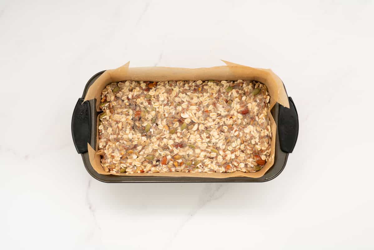 Oatmeal bread mix in a lined loaf tin.