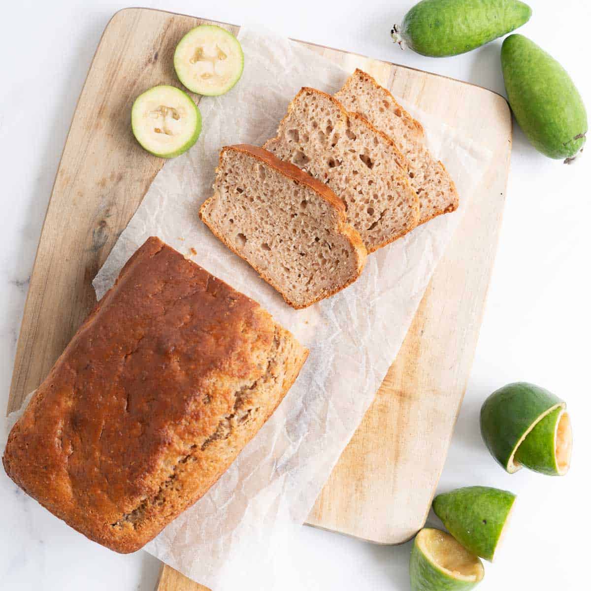 Feijoa loaf on a chopping board, three slices cut from the loaf.