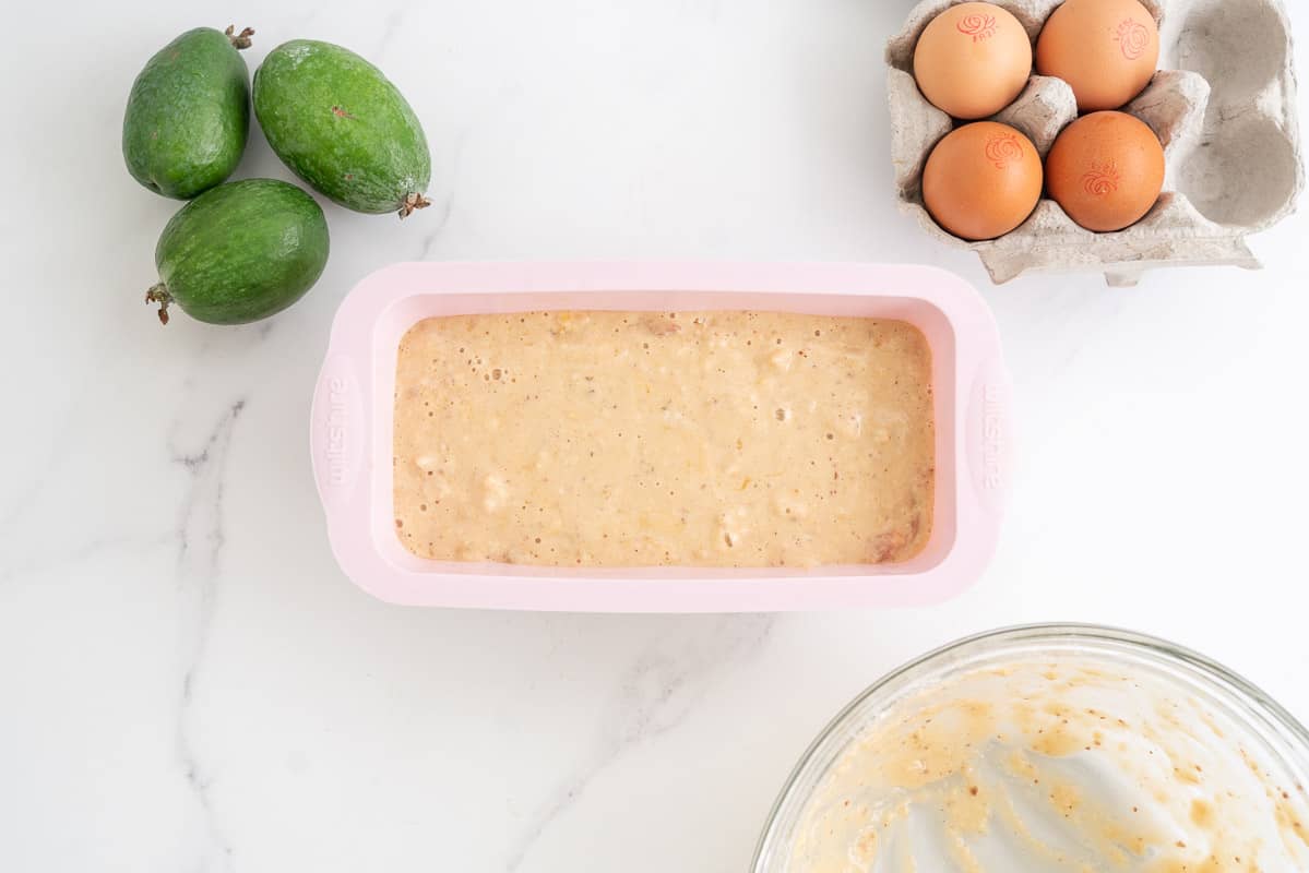 Feijoa batter poured into a pink loaf tin, ready to be baked.