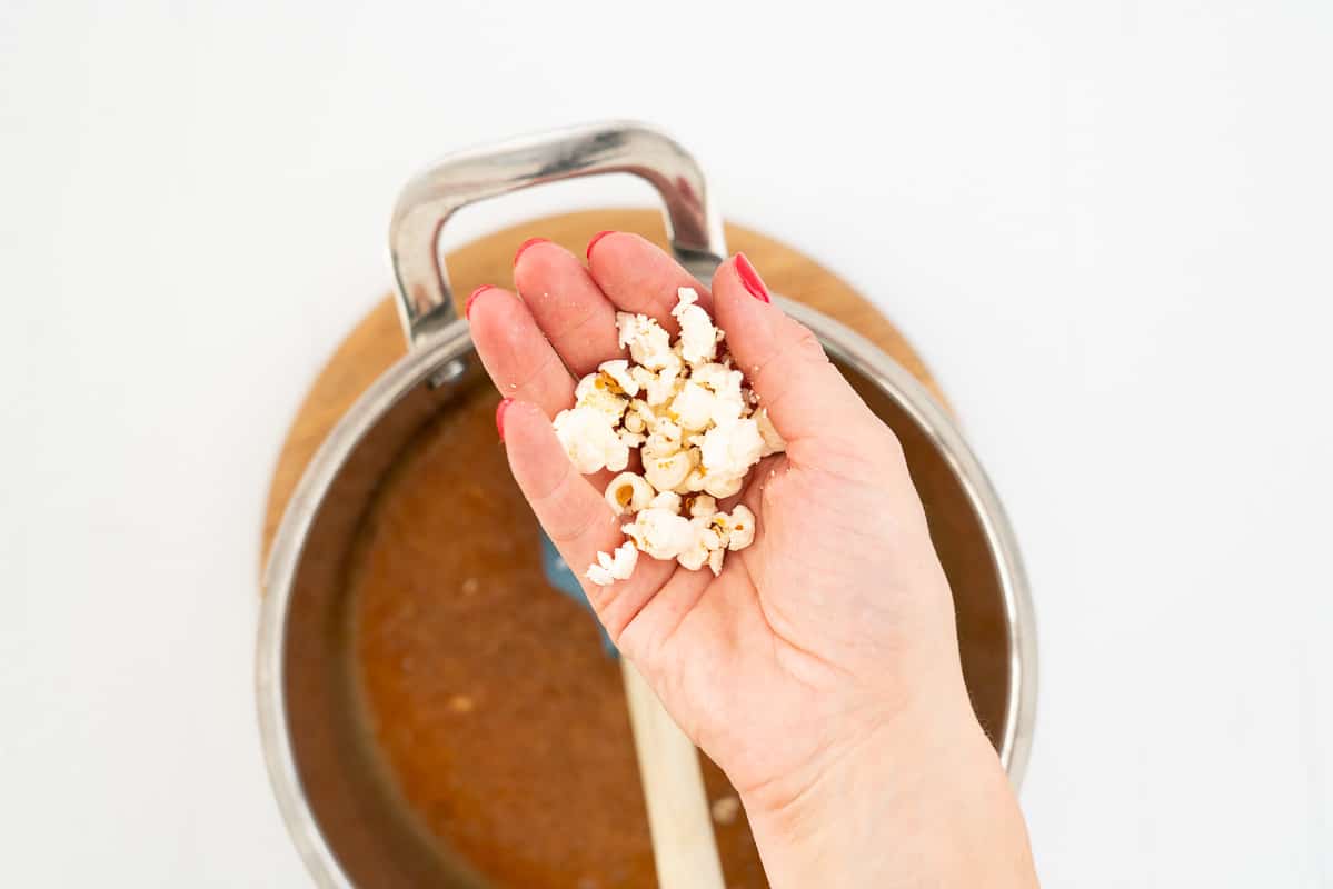 Womwns hand holding slightly crushed popcorn.