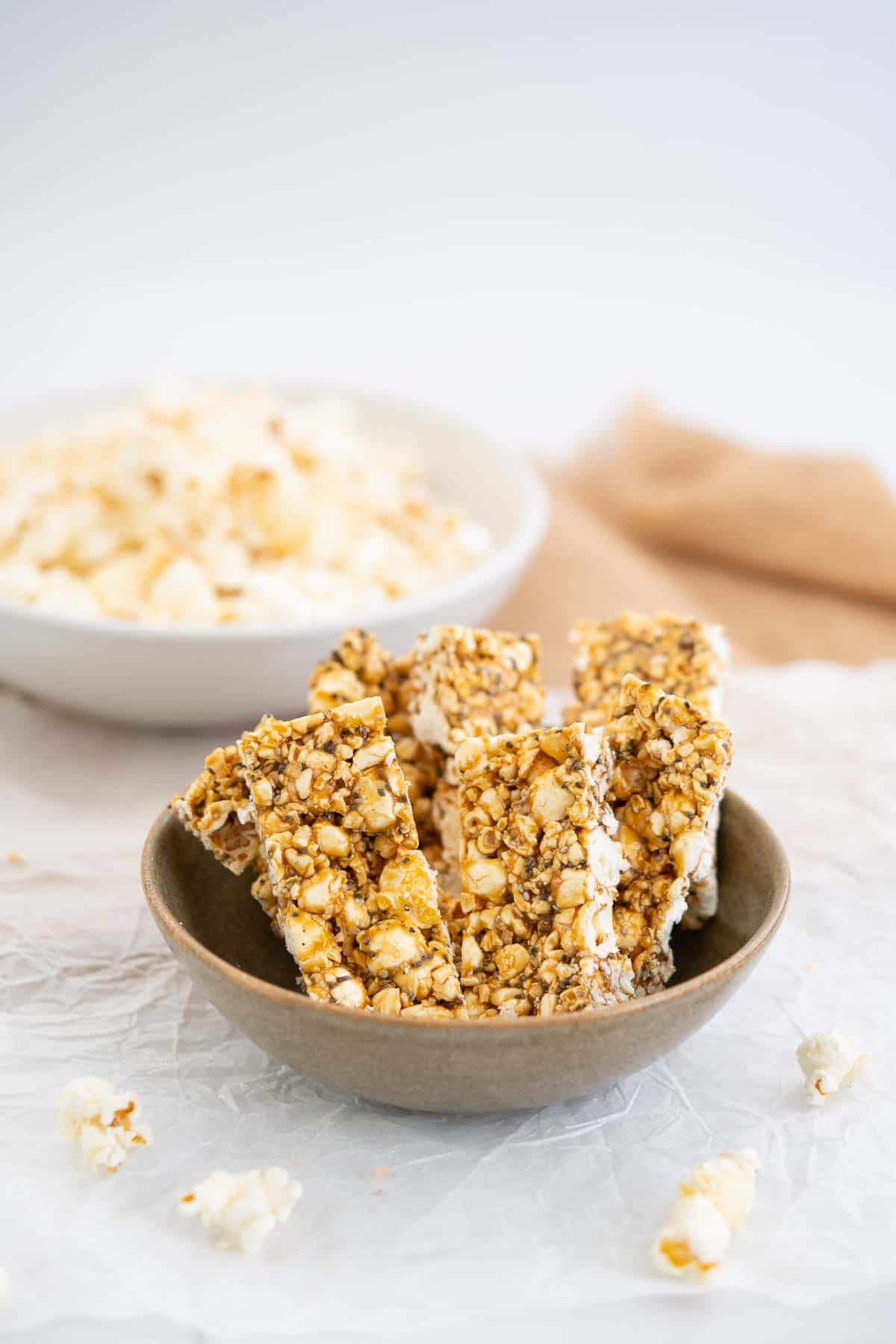 Brown ceramic bowl filled with 6 popcorn bars, a bowl of popcorn in the background.