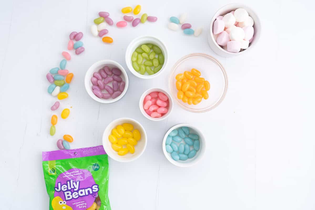 Jelly beans sorted into six small bowls by colour.